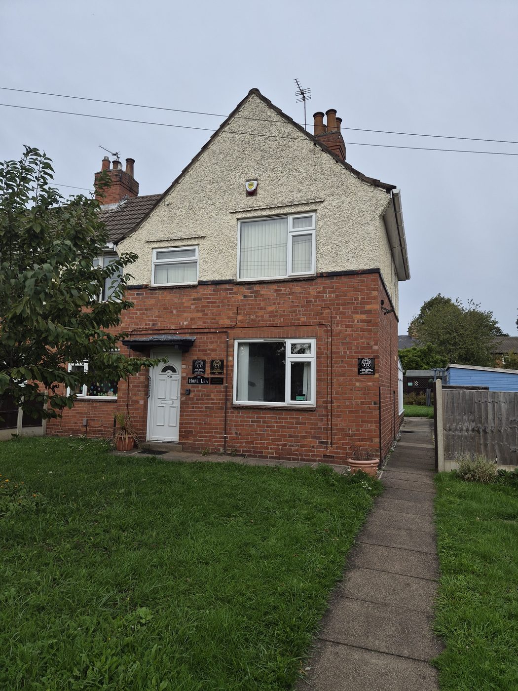 The front of Hope Lea at 150 Watnall Road, a red-brick house with a white front door and small plaques beside it.